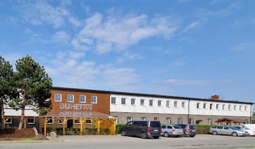 a building with cars parked in a parking lot at Penzion DUHET in Hulín
