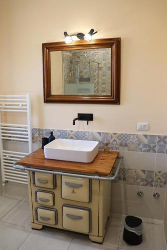 ein Bad mit einem Waschbecken und einem Wandspiegel in der Unterkunft Cascina Angelina in Casteggio