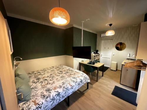 een slaapkamer met een bed en een bureau in een kamer bij Émeraude - Centre-ville /Terrasse /Parking gratuit in Roanne