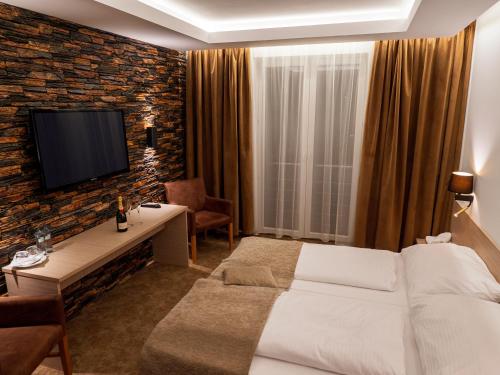 a hotel room with a bed and a tv on a brick wall at ELITE HOTEL Nová Dubnica in Nová Dubnica