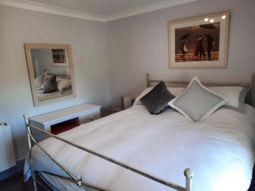 a bedroom with a white bed with two mirrors at Croak Cottage, Frogmore in South Pool