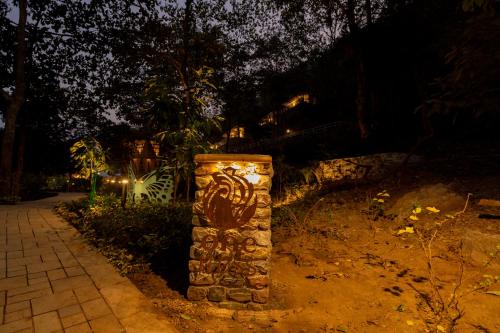 a stone pillar with a painting on it at night at ONENESS Rishikesh by Ganga Kinare - A Luxury Wilderness Resort in Rishīkesh
