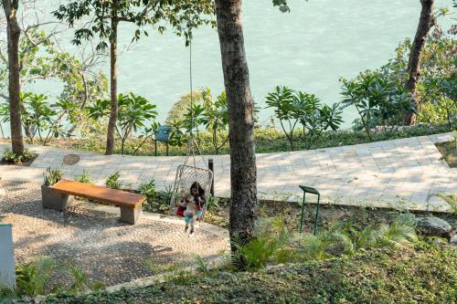 a little girl is walking on a swing next to a bench at ONENESS Rishikesh by Ganga Kinare - A Luxury Wilderness Resort in Rishīkesh