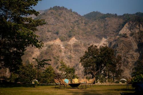 a group of chairs and a table in front of a mountain at ONENESS Rishikesh by Ganga Kinare - A Luxury Wilderness Resort in Rishīkesh