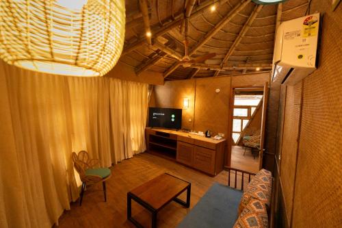 a living room with a couch and a table and a television at ONENESS Rishikesh by Ganga Kinare - A Luxury Wilderness Resort in Rishīkesh