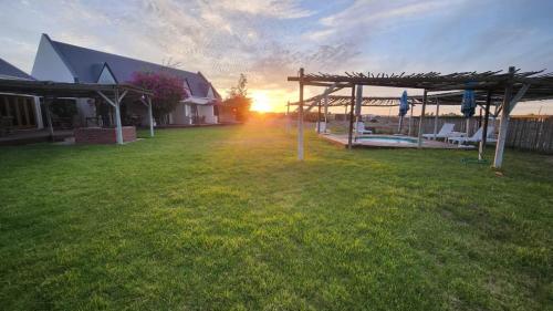 a house with the sun setting in the yard at Tortoise Trail Lodge in Langebaan