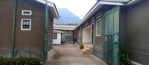 an alley between two buildings with green doors at Rwenzori Base camp tour Holiday Inn in Kasese