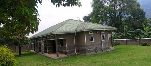 a small house with a green roof on a yard at Rwenzori Base camp tour Holiday Inn in Kasese