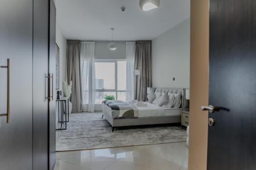 a white bedroom with a bed and a large window at Clever Guest Concorde JLT in Dubai