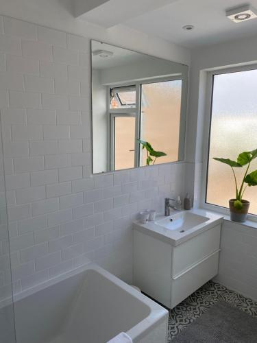 a white bathroom with a sink and a mirror at The Studio in Frinton-on-Sea