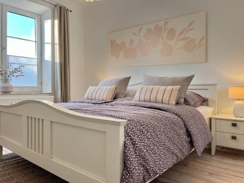 a white bedroom with a bed and a window at Apartment Perlmutt mit Balkon in Husum