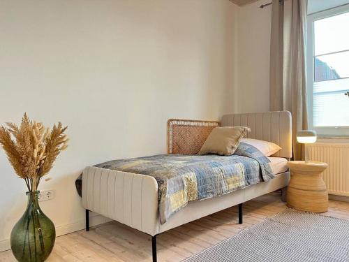 a bedroom with a bed and a vase on the floor at Apartment Perlmutt mit Balkon in Husum