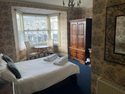 a bedroom with a bed and a table and a window at Tal Y Don Hotel in Barmouth