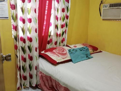 a bedroom with a bed with a curtain with flowers at Jeremiah Homestay near Masasa Beach in Batangas City