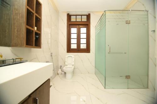 a bathroom with a toilet and a glass shower at Peshawar Barracks Hotel Estb-1867 in Peshawar