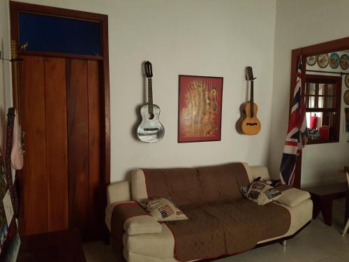 a living room with a couch and guitars on the wall at Casa Cultural Caiçara Paraty - WiFi, Vaga privativa, próxima ao Centro Histórico in Paraty