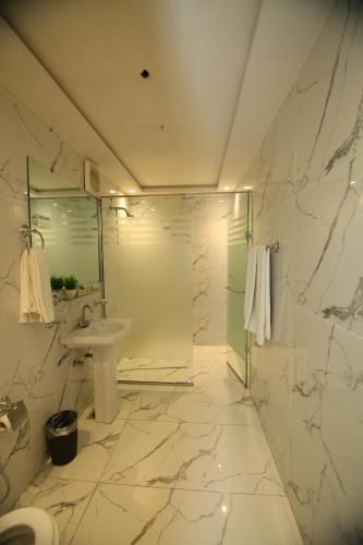 a white bathroom with a sink and a shower at Peshawar Barracks Hotel Estb-1867 in Peshawar