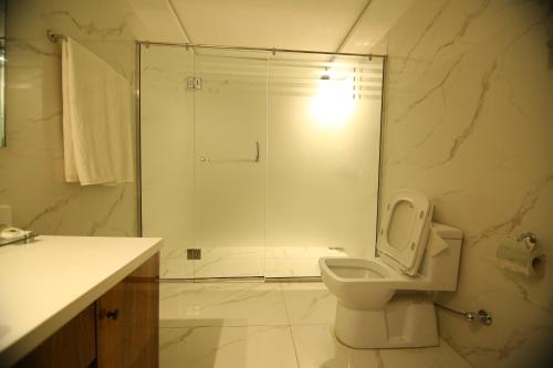 a white bathroom with a shower and a toilet at Peshawar Barracks Hotel Estb-1867 in Peshawar