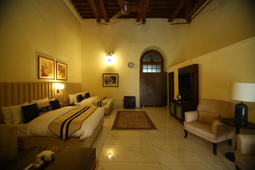 a bedroom with a bed and a living room with a couch at Peshawar Barracks Hotel Estb-1867 in Peshawar