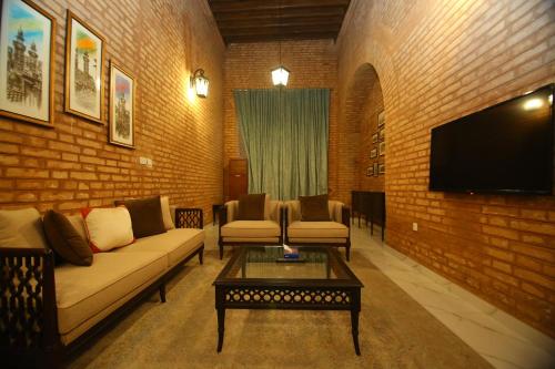 a living room with couches and a flat screen tv at Peshawar Barracks Hotel Estb-1867 in Peshawar