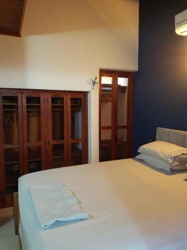 a bedroom with a white bed and wooden cabinets at Casa Cultural Caiçara Paraty - WiFi, Vaga privativa, próxima ao Centro Histórico in Paraty