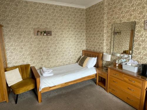 a bedroom with a bed and a dresser and a mirror at Tal Y Don Hotel in Barmouth