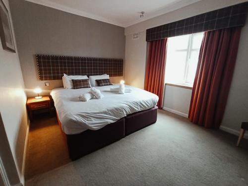 a hotel room with a large bed with a window at Anchor Hotel and Seabed Restaurant in Tarbert