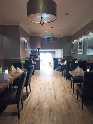 a dining room with tables and chairs and aandelier at Anchor Hotel and Seabed Restaurant in Tarbert