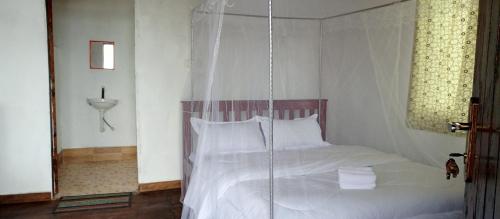 a bedroom with a white bed with a hanging canopy at Ruhija Gorilla Guest House in Kabale