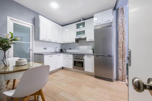 a kitchen with white cabinets and a table and a refrigerator at 1 bedroom 1 bathroom furnished - Sol - Downtown - Minty Stay in Madrid