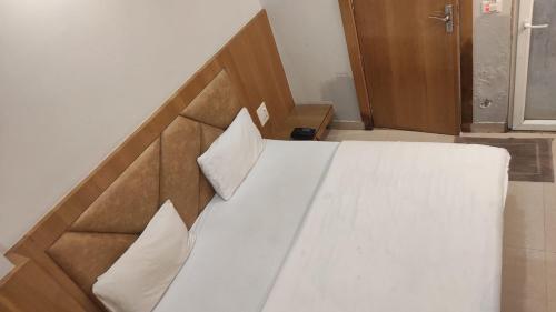 a bedroom with a bed with white sheets and pillows at HOTEL GANGARANI in Haridwār