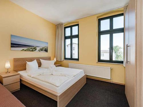 ein Schlafzimmer mit einem großen Bett und zwei Fenstern in der Unterkunft Strandvilla Ostpreussen - Dependance Strandhus in Ahlbeck