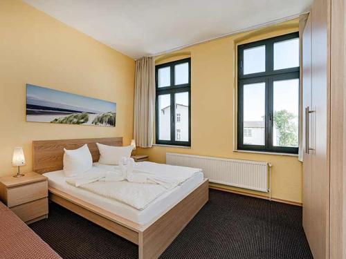 Un dormitorio con una cama grande y dos ventanas. en Strandvilla Ostpreussen - Dependance Strandhus, en Ahlbeck