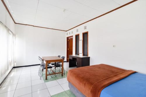 Schlafzimmer mit einem Bett, einem Tisch und einem Schreibtisch in der Unterkunft Abang Hotel Ciwidey in Bandung
