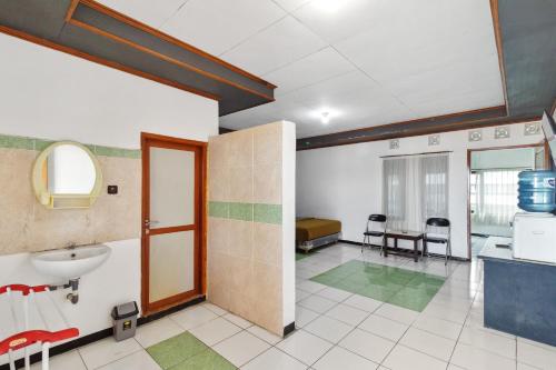 ein Bad mit einem Waschbecken und ein Bett in einem Zimmer in der Unterkunft Abang Hotel Ciwidey in Bandung