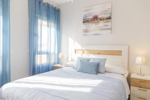 a bedroom with a large white bed with blue curtains at Cubo's Apartamento Perla del Sol 3I in Torremolinos