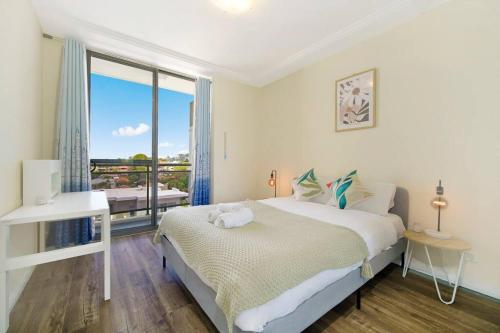 ein weißes Schlafzimmer mit einem Bett und einem großen Fenster in der Unterkunft Shyline Views - Beautiful Condo In Wolli Creek in Sydney
