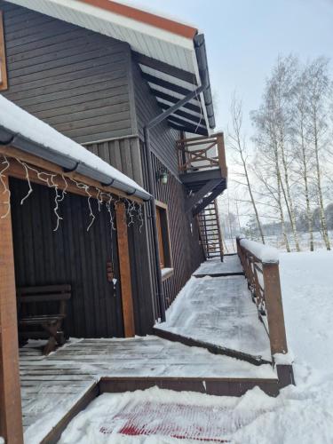a cabin with snow on the porch and a staircase at Piligrimo sodyba in Kadarės