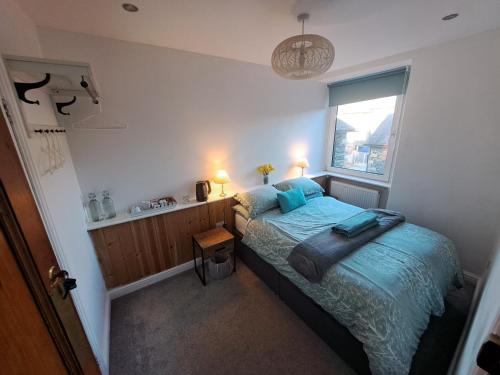 a bedroom with a bed with a blue comforter and a window at Birch Tree House in Windermere