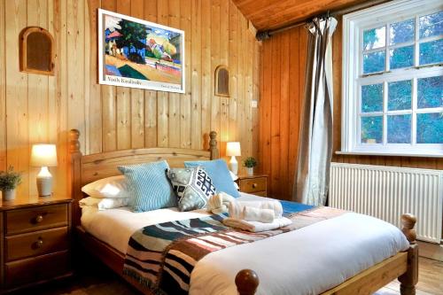a bedroom with a bed in a room with wooden walls at 3 Bed Cabin in the Woods in Barham