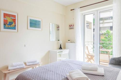 a white bedroom with a bed and a balcony at Positive vibes: Athens studio in Athens
