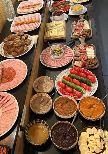 un buffet avec de nombreuses assiettes de nourriture sur une table dans l'établissement Podina Resort Hotel & Spa, à Ungureni