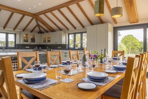 a dining room with a wooden table with wine glasses at Wild Meadow Barn in Aylsham