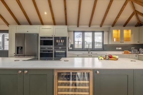 a kitchen with gray cabinets and a white counter top at Wild Meadow Barn in Aylsham