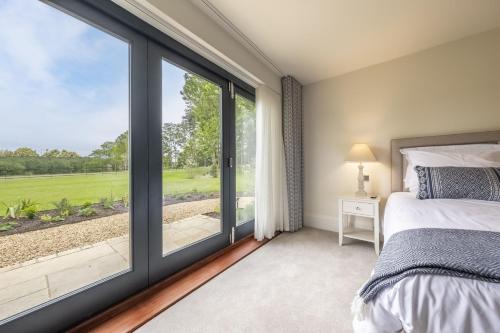 a bedroom with a bed and a large window at Wild Meadow Barn in Aylsham