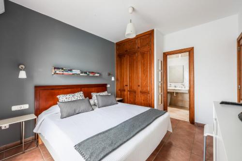 een slaapkamer met een wit bed en een houten hoofdeinde bij VILLAS LANZAROTE LOS ALTOS by NEW LANZASUITES Villa SERENA in Playa Blanca