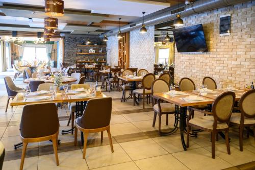 un ristorante con tavoli e sedie in legno e un muro di mattoni di MV Monogram a Inđija