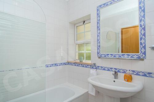 a white bathroom with a sink and a mirror at Quinta do Rosal, Casa Rosa in Carvoeiro