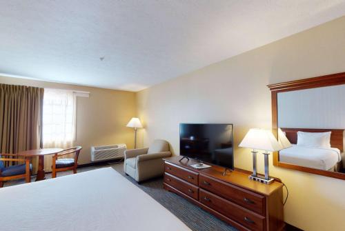 a hotel room with a bed and a flat screen tv at Ramada by Wyndham Strasburg - Shenandoah Valley in Strasburg