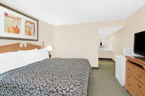 a hotel room with a bed and a flat screen tv at Days Inn by Wyndham Attalla in Attalla
